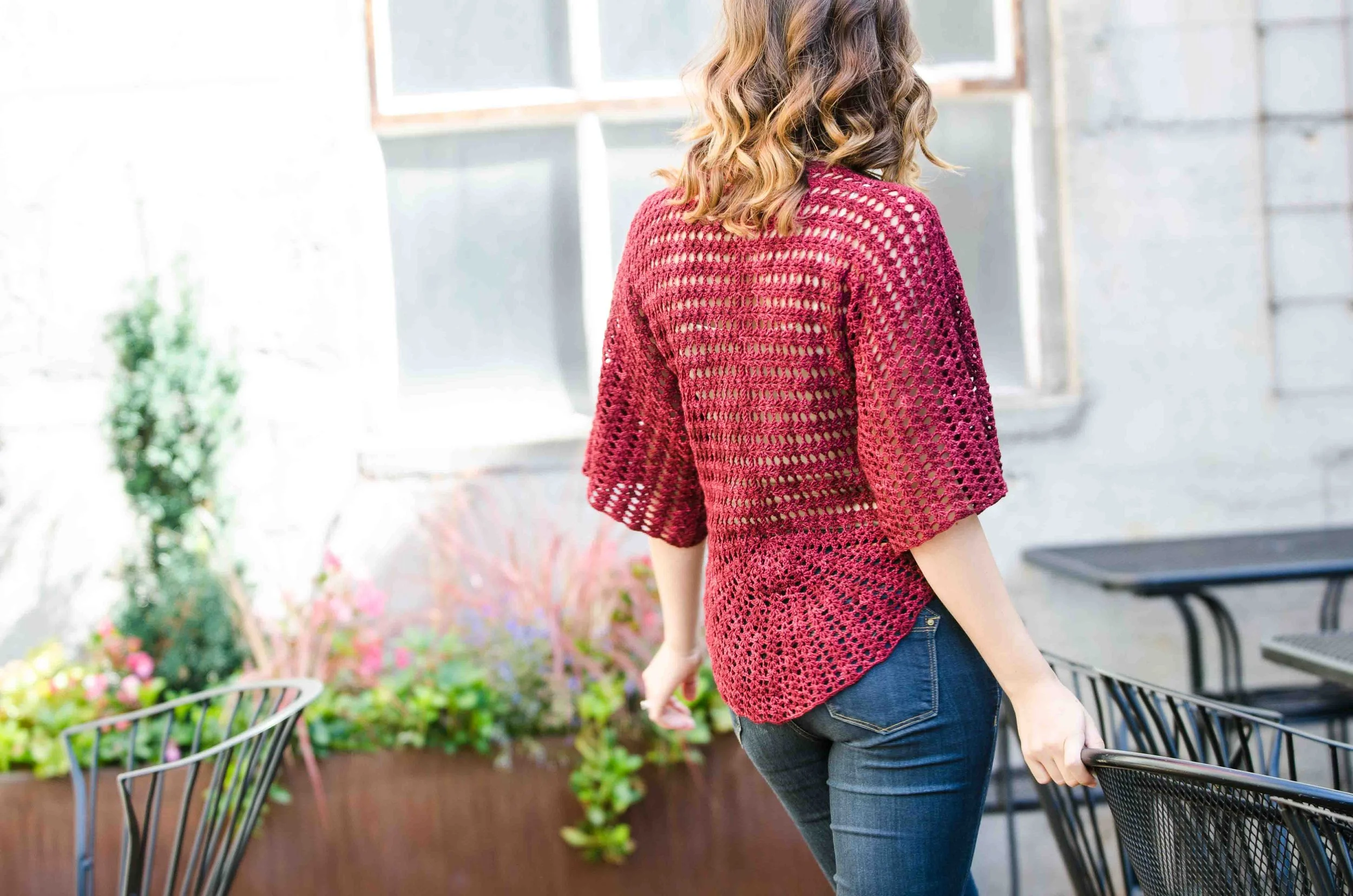 A young woman showing the back of a red lace crochet circle-t top