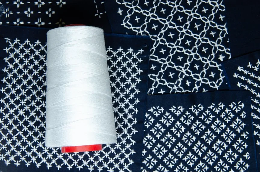 Hitomezashi sashiko stitch patterns on blue fabric
