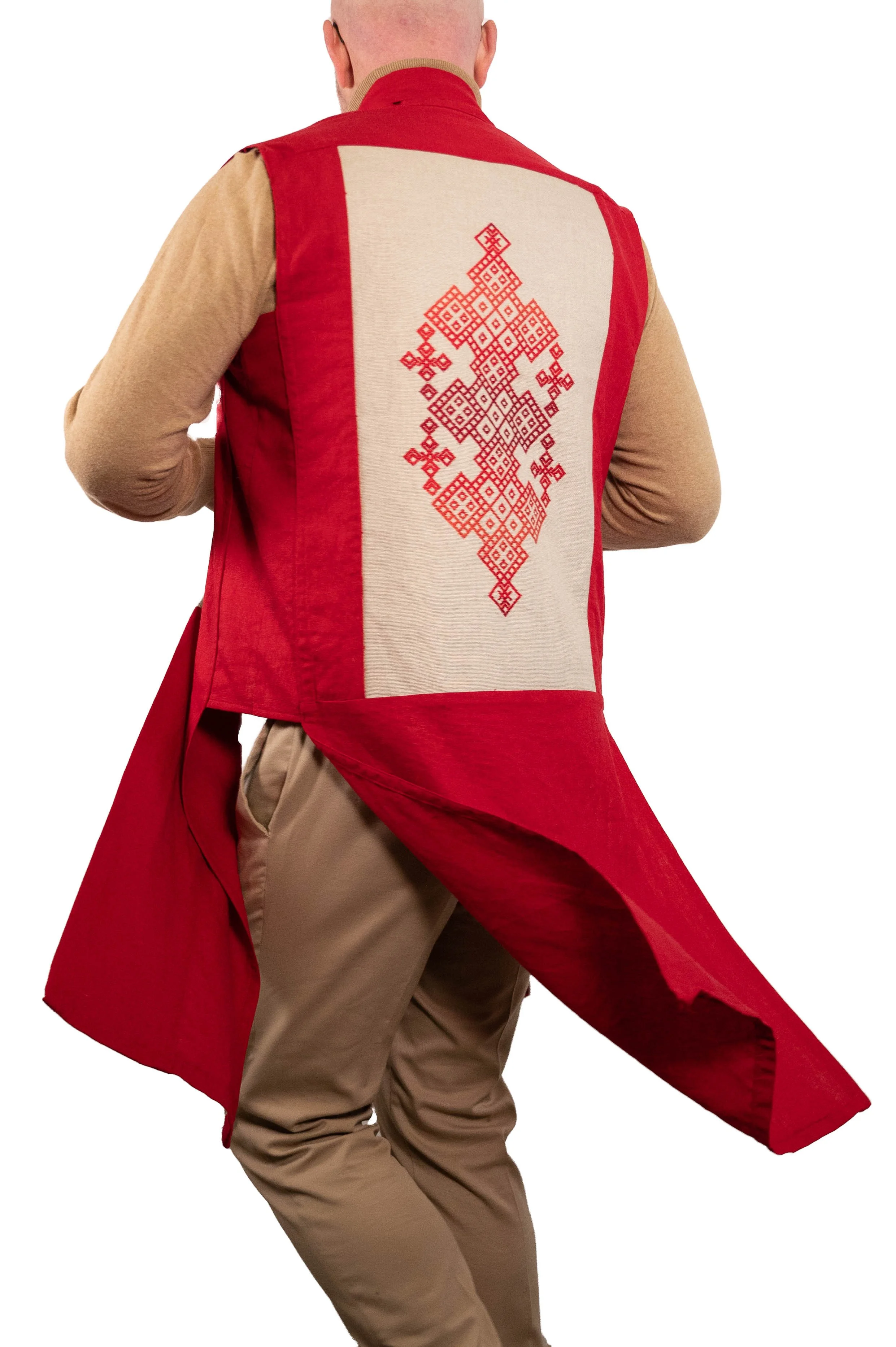 Back view of a person wearing a red and beige vest with intricate red cross-stitch embroidery on the back, paired with a tan shirt and khaki pants.