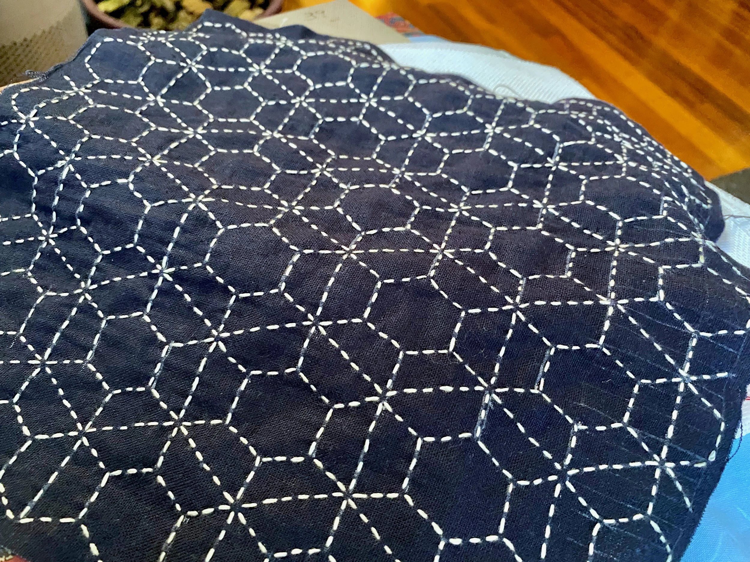 Close-up of dark fabric with white geometric stitched pattern of hexagons and stars.