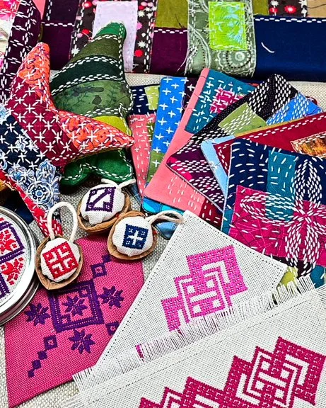 Colorful handmade quilted fabric pieces and embroidered items on a table.