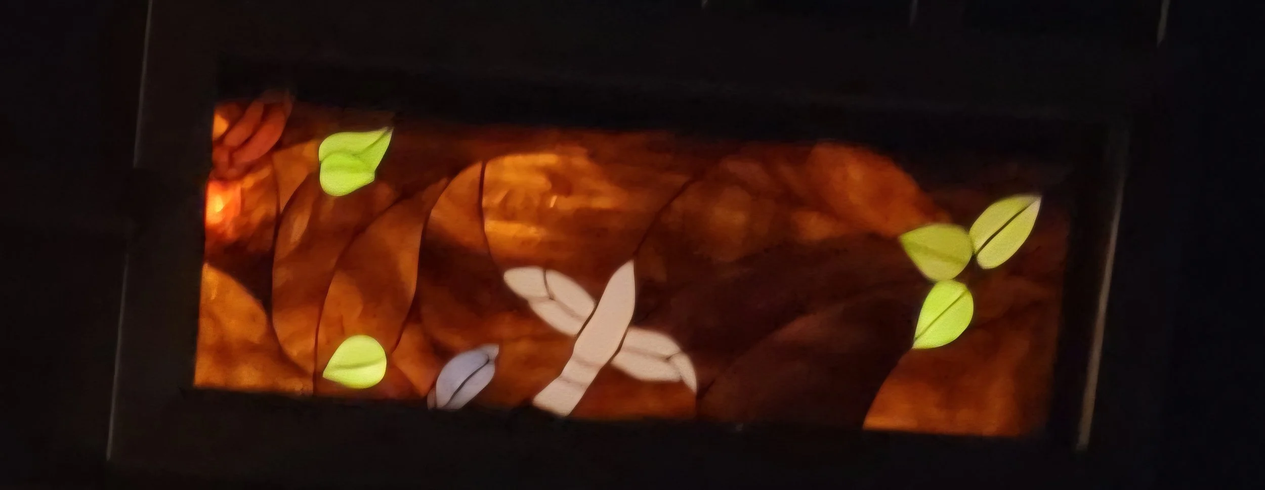 Decorative wall sconce with a floral design featuring illuminated leaves in white and yellow on a brown background