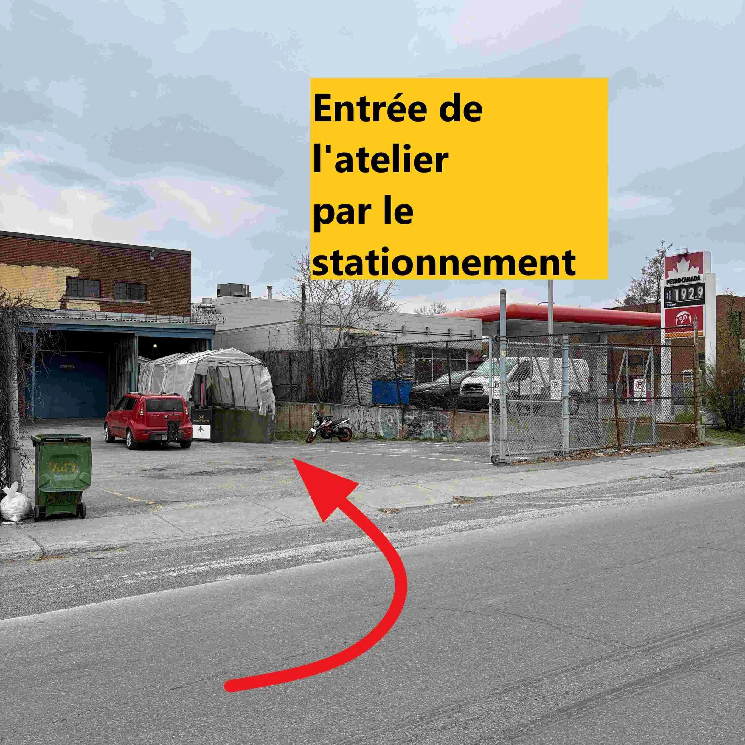 Panneau jaune indiquant l'entrée de l'atelier de stationnement, dans un environnement urbain avec bâtiments et une station-service