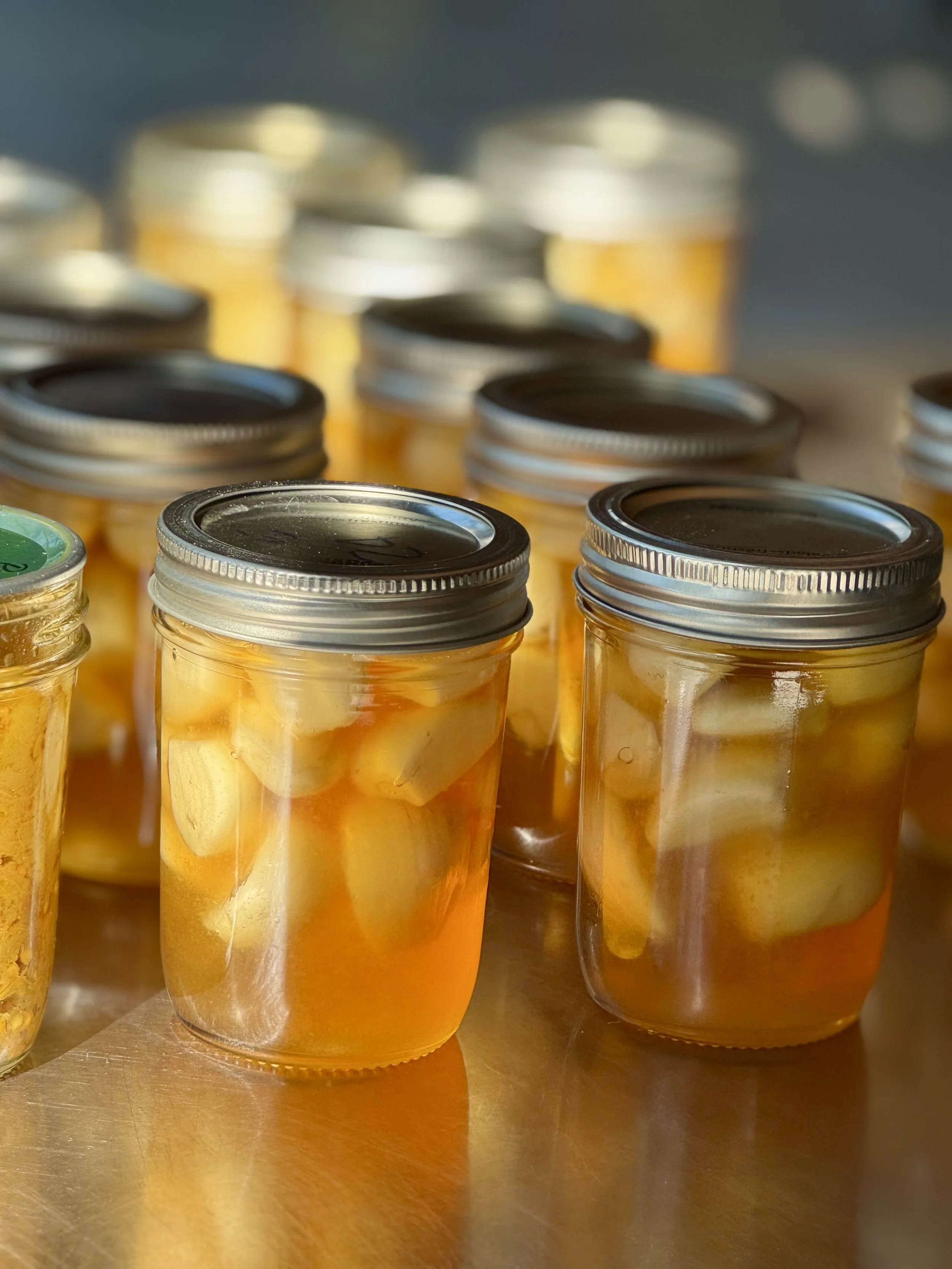 Bocaux en verre contenant des légumes marinés, comme des gousses d'ail, dans de l'huile ou du vinaigre.