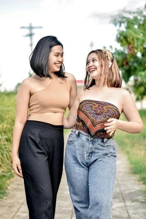 Two women with their arms around each other, smiling and walking.