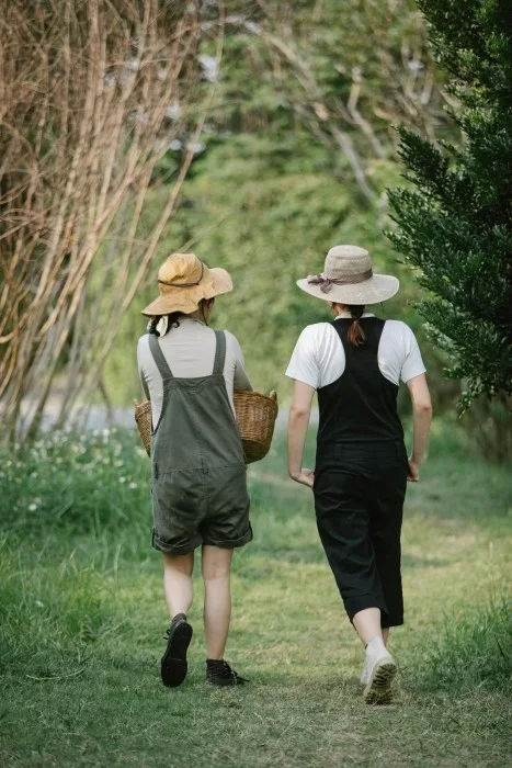 Two woman walking on a grass path together.