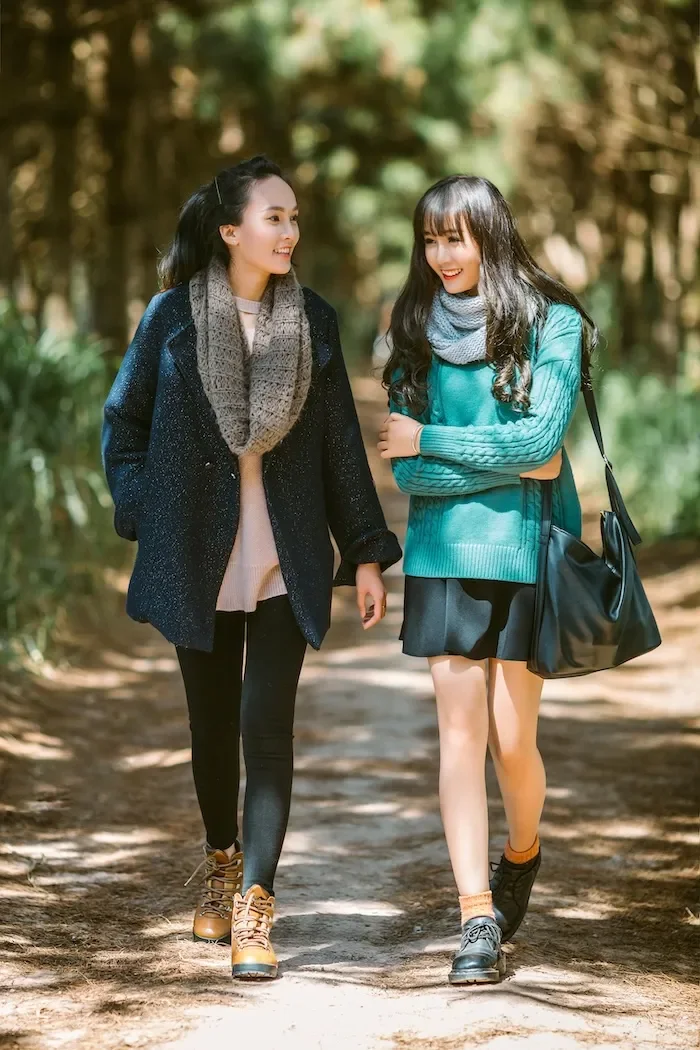 Two women walking on a path together outside.