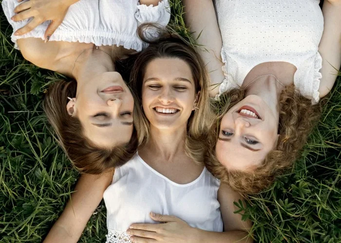Three woman laying on their backs in the grass.