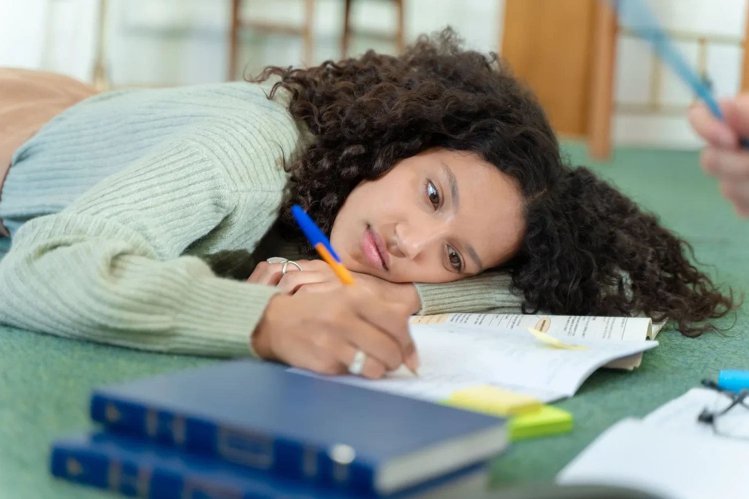 teen girl writing in notebook with her head rested on her arm