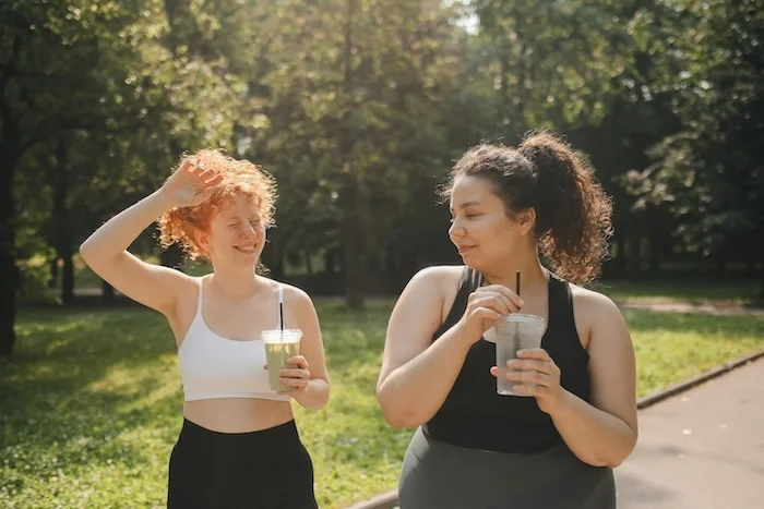 Two women walking together outside carrying matcha.