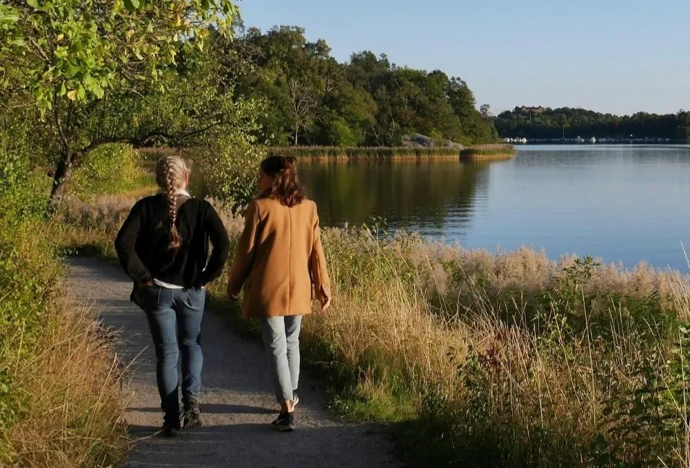 Two women walking down a path while talking to eachother.