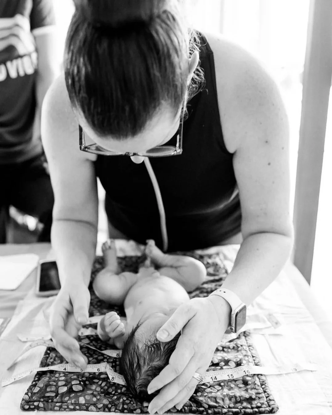 A licensed midwife performing a newborn exam at a home birth in Los Angeles.