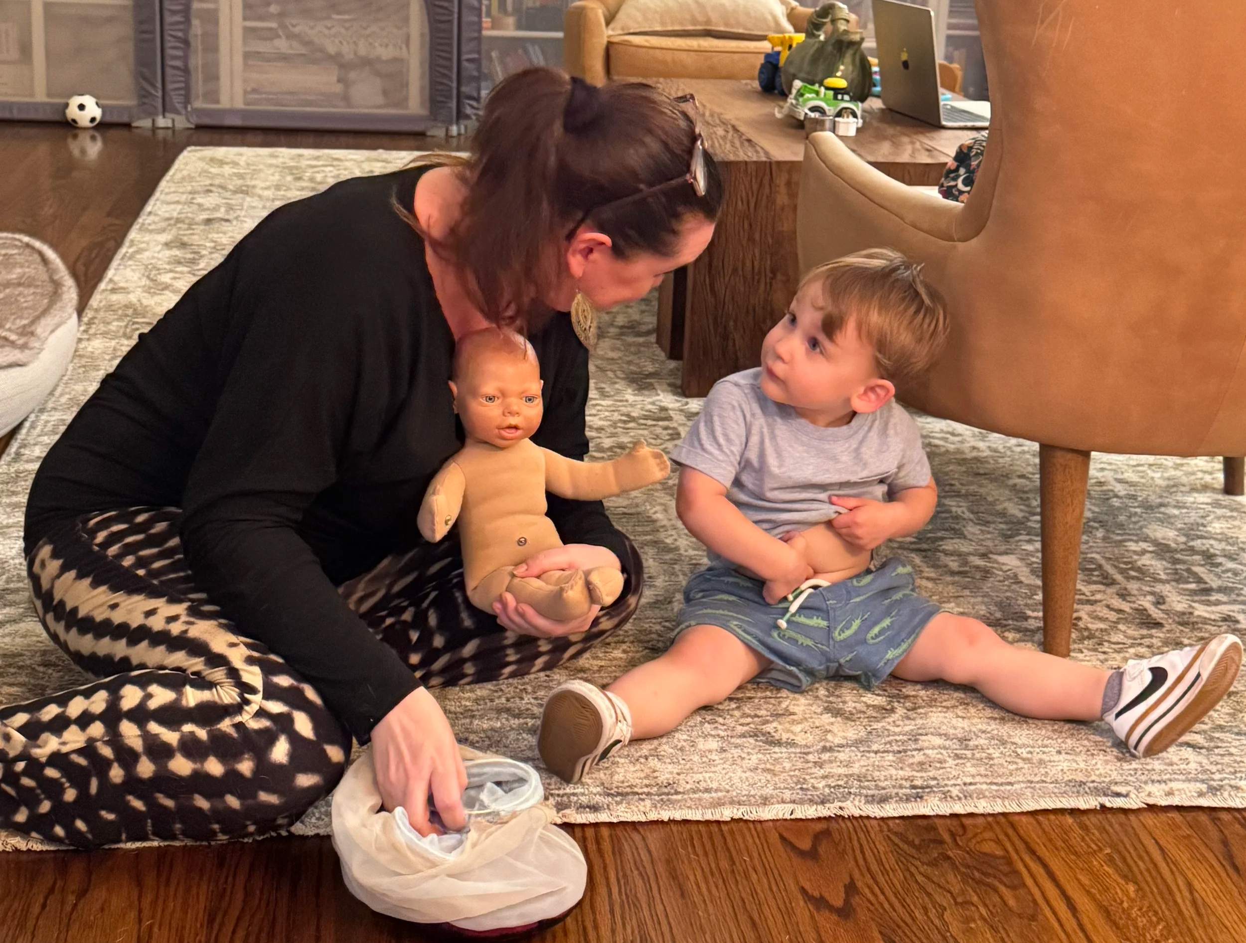 A licensed midwife sitting and chatting with a toddler about his new baby sibling that is on the way. Licensed midwife helps prepare a toddler for the birth of a new sibling in a refresher childbirth class in Los Angeles.