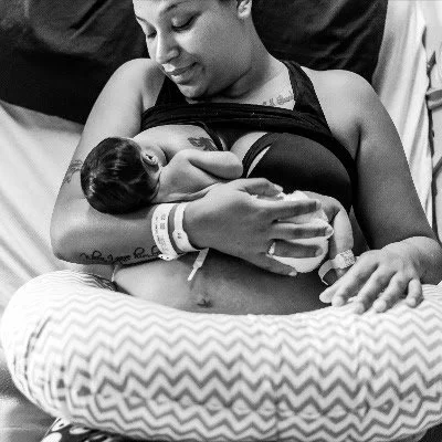 A woman holding a newborn baby in her arms in a hospital bed.