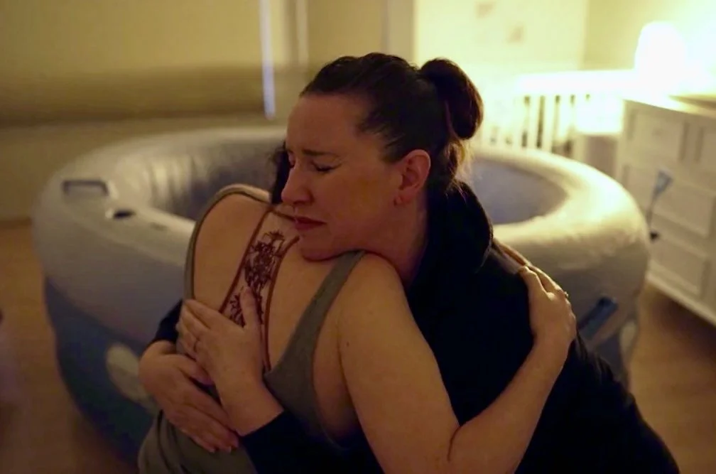 A licensed midwife hugging a woman in labor at a water birth in Los Angeles.