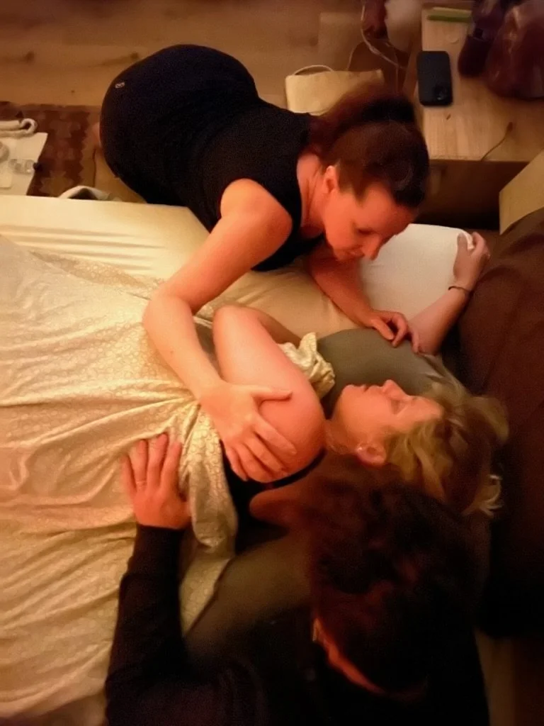 A laboring pregnant women is being supported by her midwife or doula while in labor at home. 