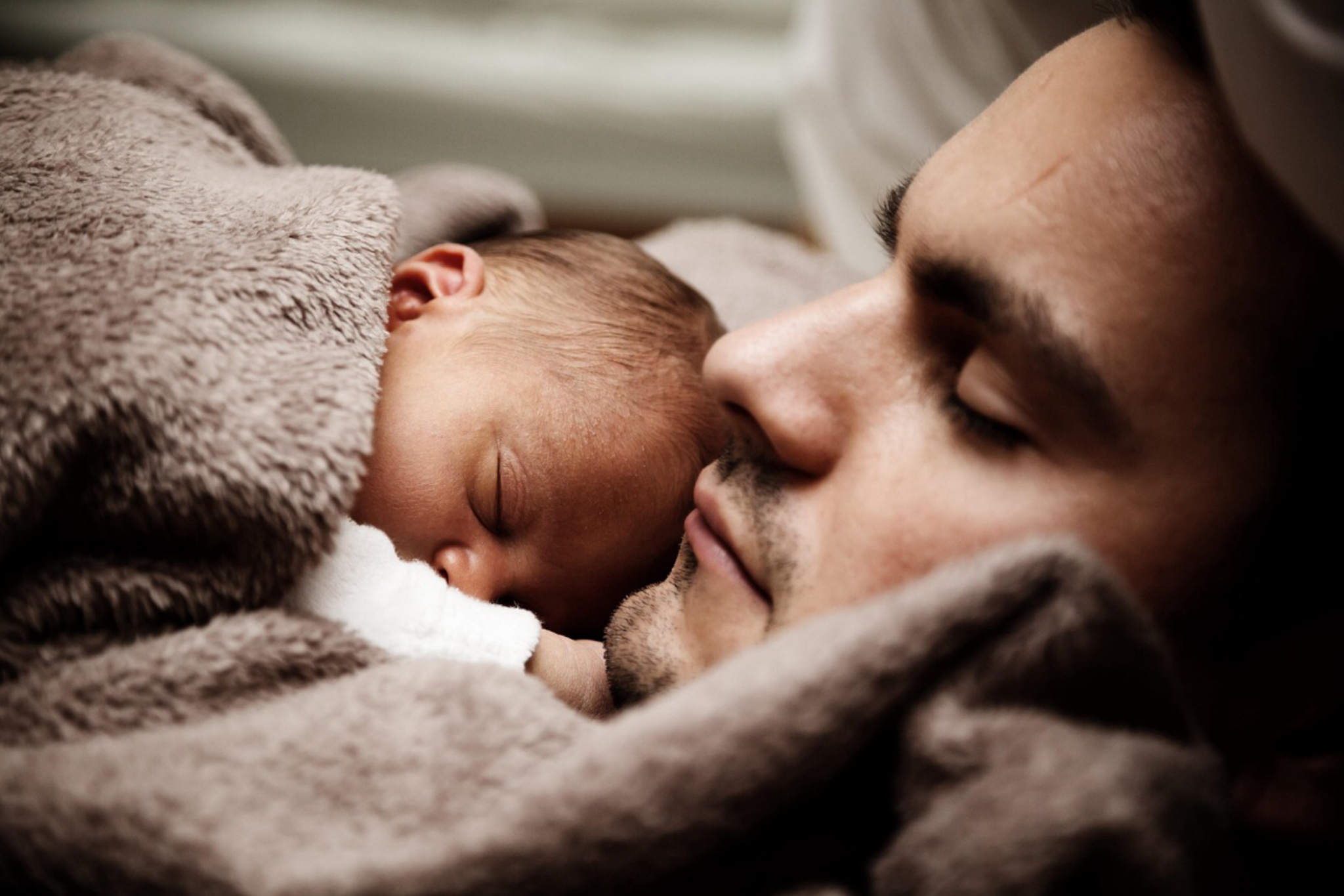 A man cuddling a newborn baby after a peaceful water birth at home in Los Angeles.