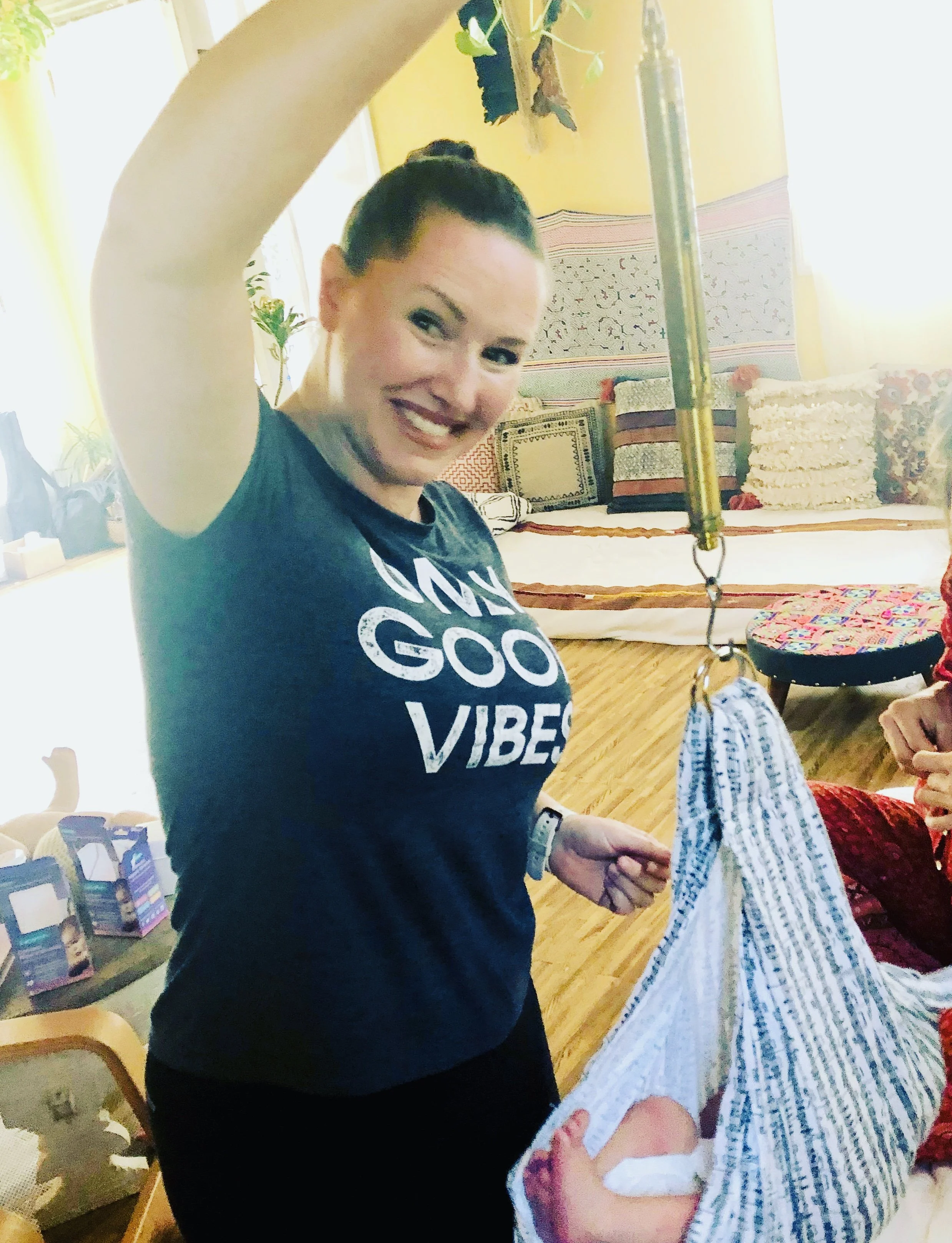 A midwife is holding a baby wrapped in a striped blanket with a measuring device attached.