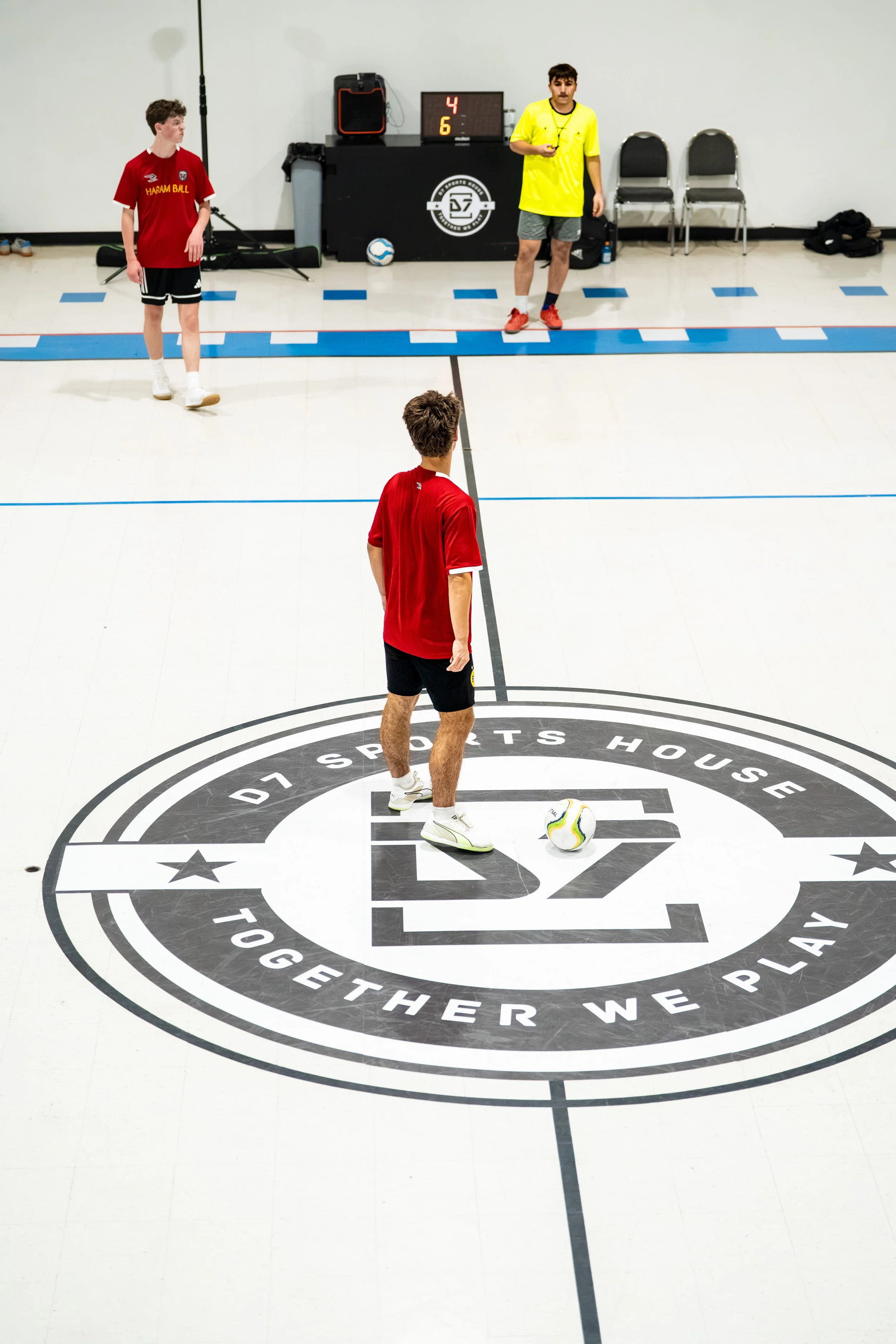 People in athletic clothing and white shoes standing behind a green barrier on a court.
