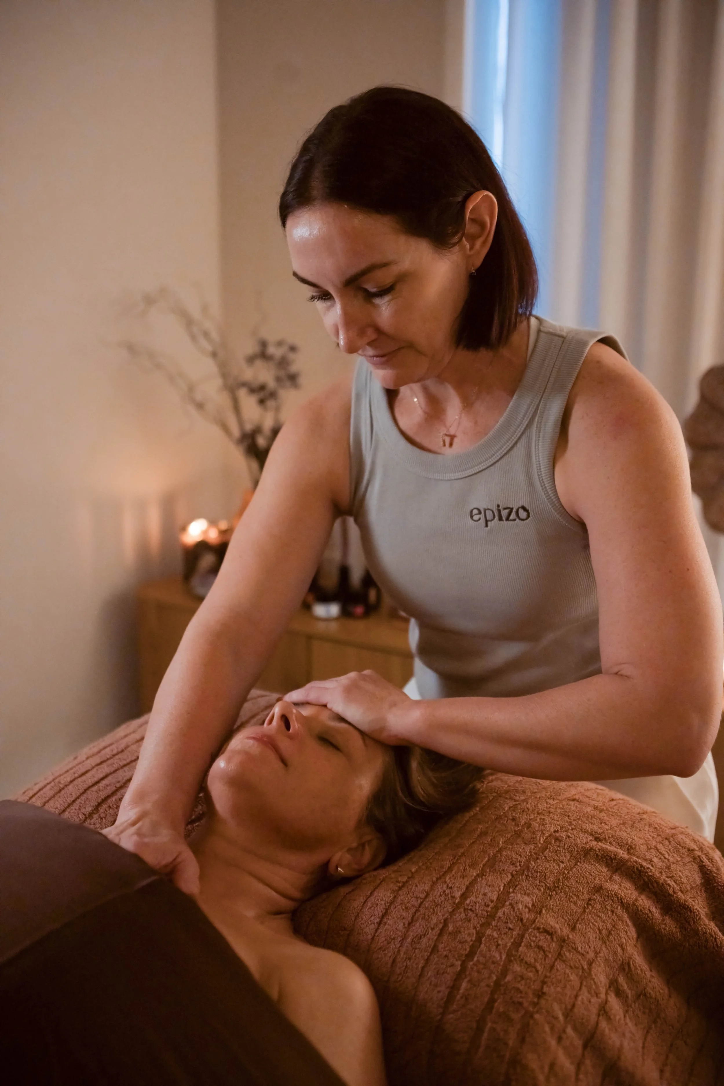A massage therapist performing a massage on a woman in a treatment room.