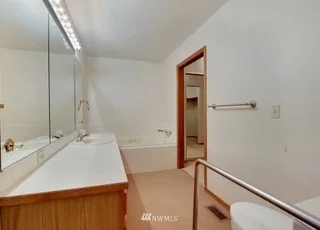 Bathroom with lighted vanity, sink and grab bar next to toilet at 1300 28th Avenue Court, Milton, WA 98354