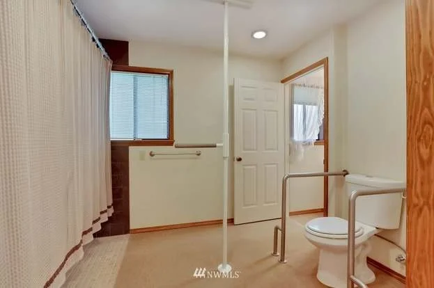 Bathroom with roll in shower and toilet with grab bars on both sides at 1300 28th Avenue Court, Milton, WA 98354