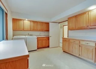 Utility room with upper and lower storage cabinets, roll under counter and washer and dryer at 1300 28th Avenue Court, Milton, WA 98354