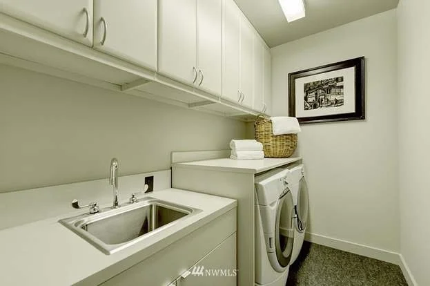 Utility room with front loading washer/dryer, sink with lower cabinet and row of upper cabinets at 715 2nd Ave #1703 Seattle WA 98104