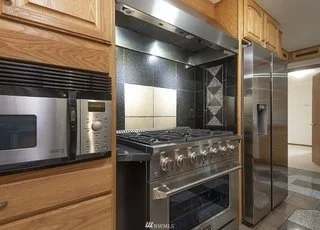 Kitchen with front knobbed range, lowered microwave and side by side fridge at 19607 Heinz Pl, Lynnwood, WA 98036