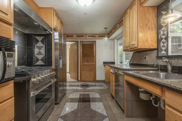 Kitchen with wood cabinets, granite counter tops and colorful back splashes at 19607 Heinz Pl, Lynnwood, WA 98036