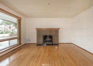 Living area with hardwood flooring, fire place and floor to ceiling windows at 19607 Heinz Pl, Lynnwood, WA 98036