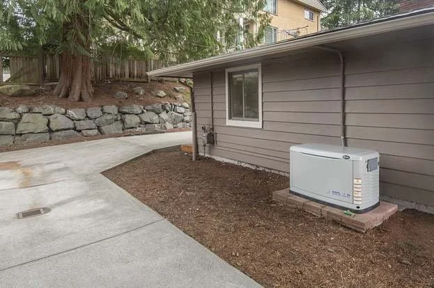 Back of house with concrete sidewalks and generator at 19607 Heinz Pl,Lynnwood, WA 98036