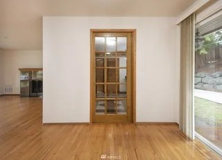 Living area with back door slider, hardwood flooring and glass paned door into kitchen at 19607 Heinz Pl, Lynnwood, WA 98036