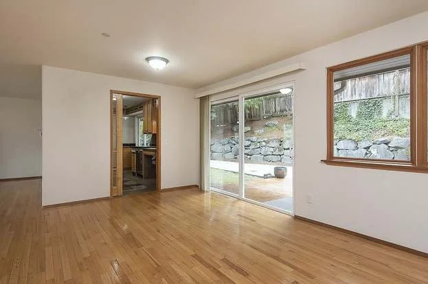 Living room area with back door sliding doors, hardwood flooring and entry into kitchen at 19607 Heinz Pl, Lynnwood, WA 98036