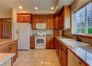 Kitchen with double sinks, white appliances and tiled flooring at 104 Quail Lane Cashmere WA 98815
