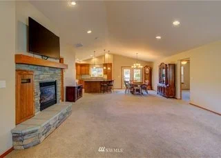 Open floor living room with fire place, stone hearth and carpeting at 104 Quail Lane Cashmere WA 98815