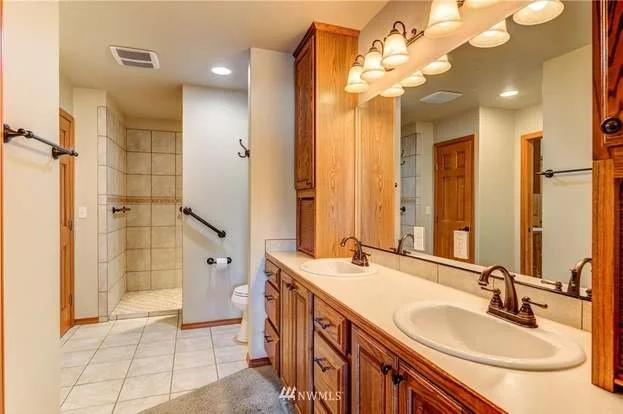 Bathroom with double sink vanity leading into toilet and shower area at 104 Quail Lane Cashmere WA 98815