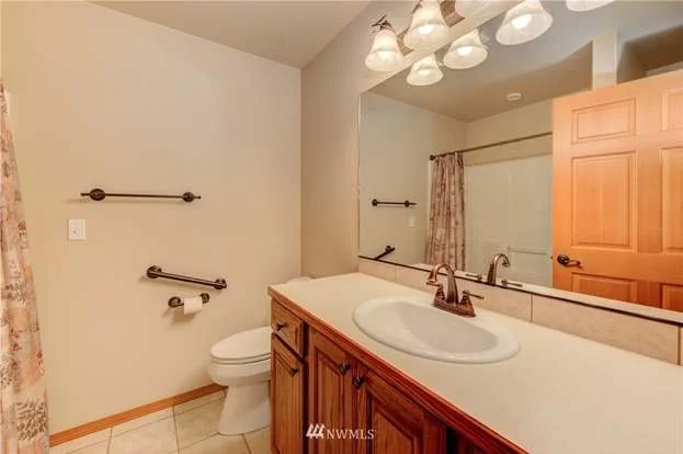 Sink and lit vanity with handle bars next to toilet at 104 Quail Lane Cashmere WA 98815