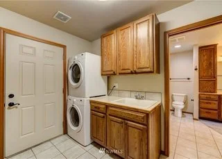 Utility room with stacked washer/dryer, upper and lower cabinets and sink at 104 Quail Lane Cashmere WA 98815
