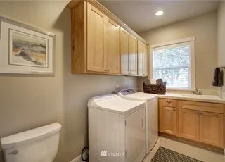 Utility room with toilet, washer/dryer, upper/lower cabinets at 2125 118th Ave E Edgewood WA 98372