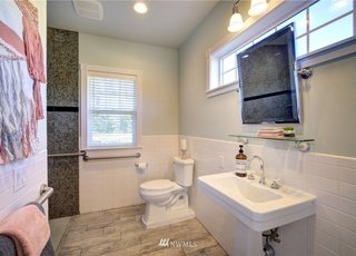 Bathroom with tiled floors, roll under sink, adjustable mirror and hand rail next to toilet at 2125 118th Ave E Edgewood WA 98372