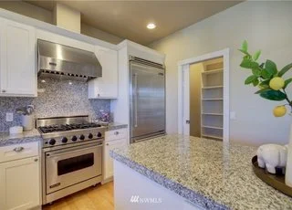 Kitchen with island, stainless steel and pantry with pocket door at 2125 118th Ave E Edgewood WA 98372