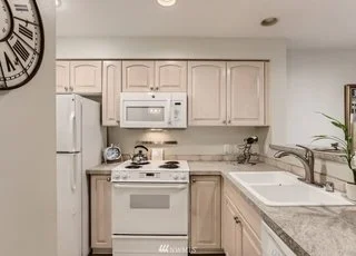 Kitchen with upper and lower cabinets, double sinks and white appliances at 2530 15th Ave W #508 Seattle WA 98119