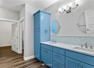 Bathroom with lower cabinets, tall linen closet and round mirrors over double sinks at 112 Skyhawk Dr Toledo WA 98591