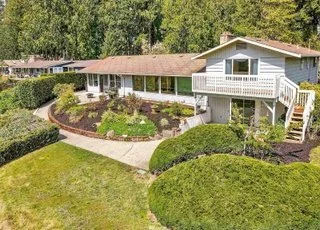 Back view of home with landscaped gardens, expansive lawn and stairway to upper level of home at 21700 Calhoun Road Monroe, WA 98272