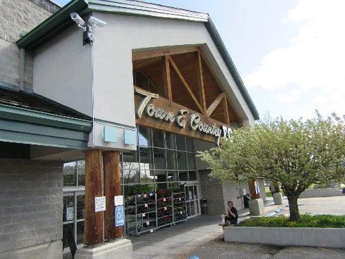 Exterior of a retail store with signage reading 'Town & Country' and a glass storefront, surrounded by trees and a parking lot.
