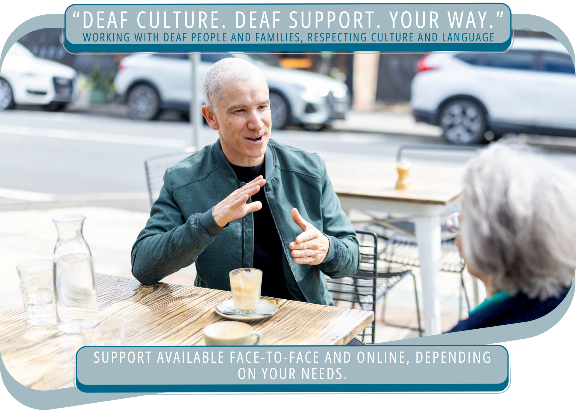 A man engaged in conversation with an older woman at an outdoor cafe, with cars parked in the background, promoting support for deaf culture and communication options. They are using Auslan sign language to communicate.