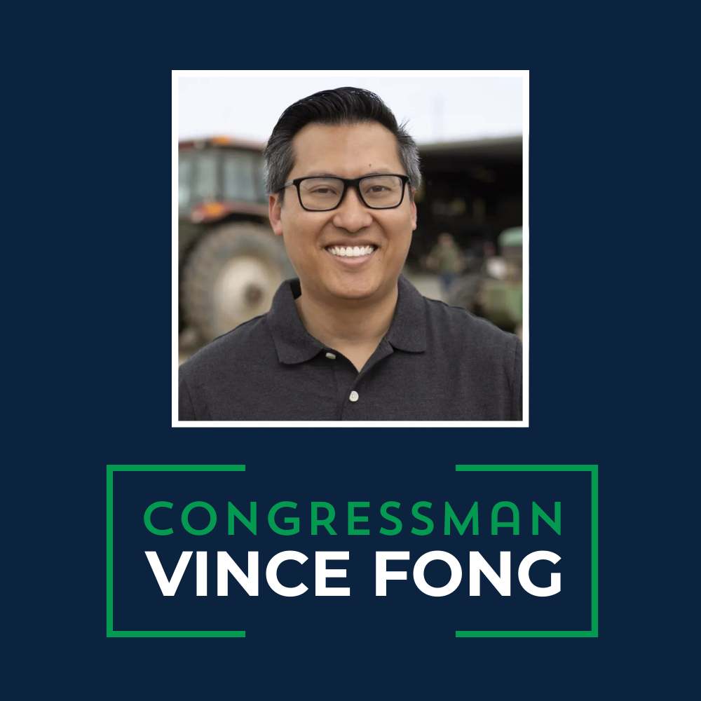 Portrait of Vince Fong, a man with black hair, glasses, wearing a dark polo shirt, smiling, with a tractor in the background, representing a candidate for Congress.