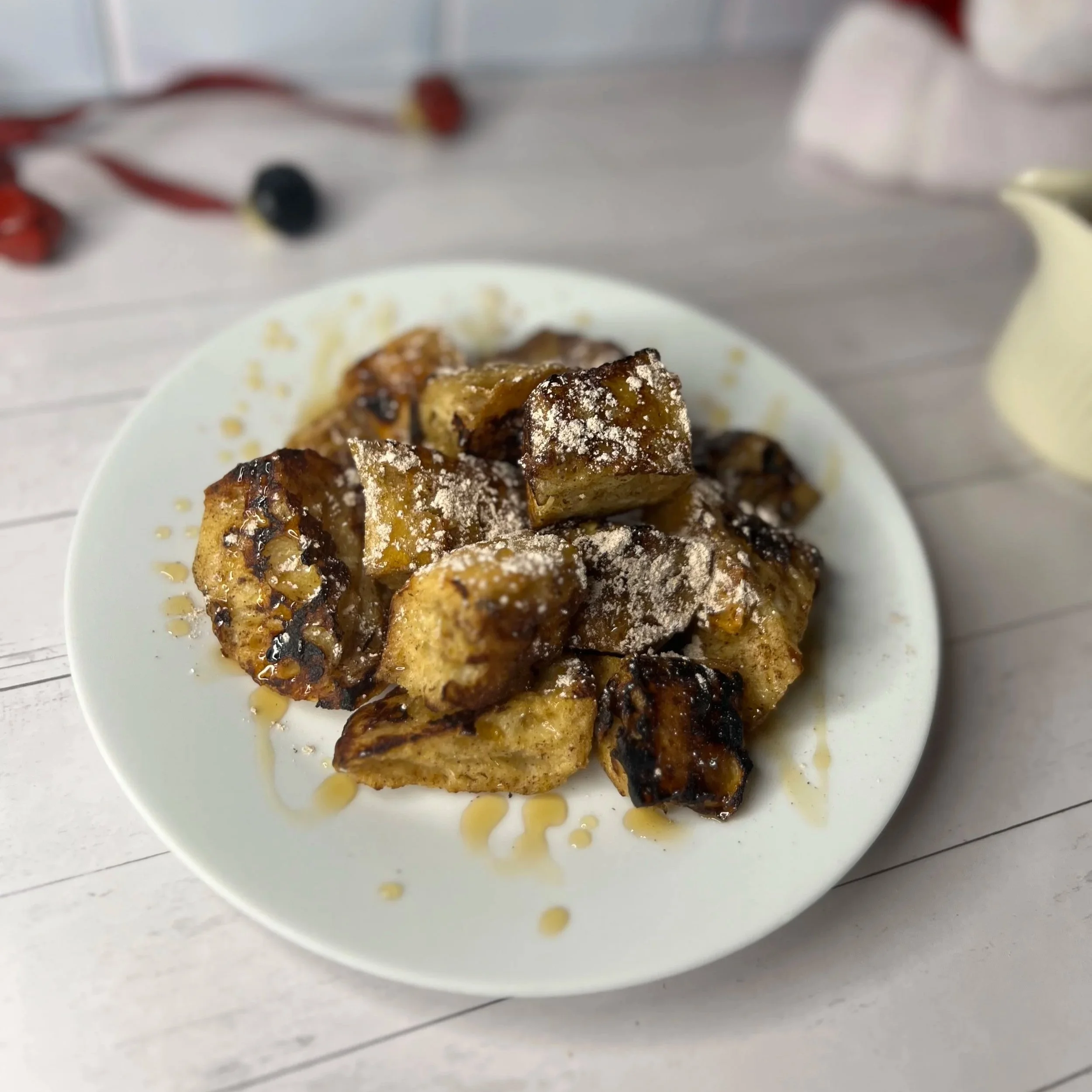 Cooked bananas with syrup and powdered sugar on a white plate.
