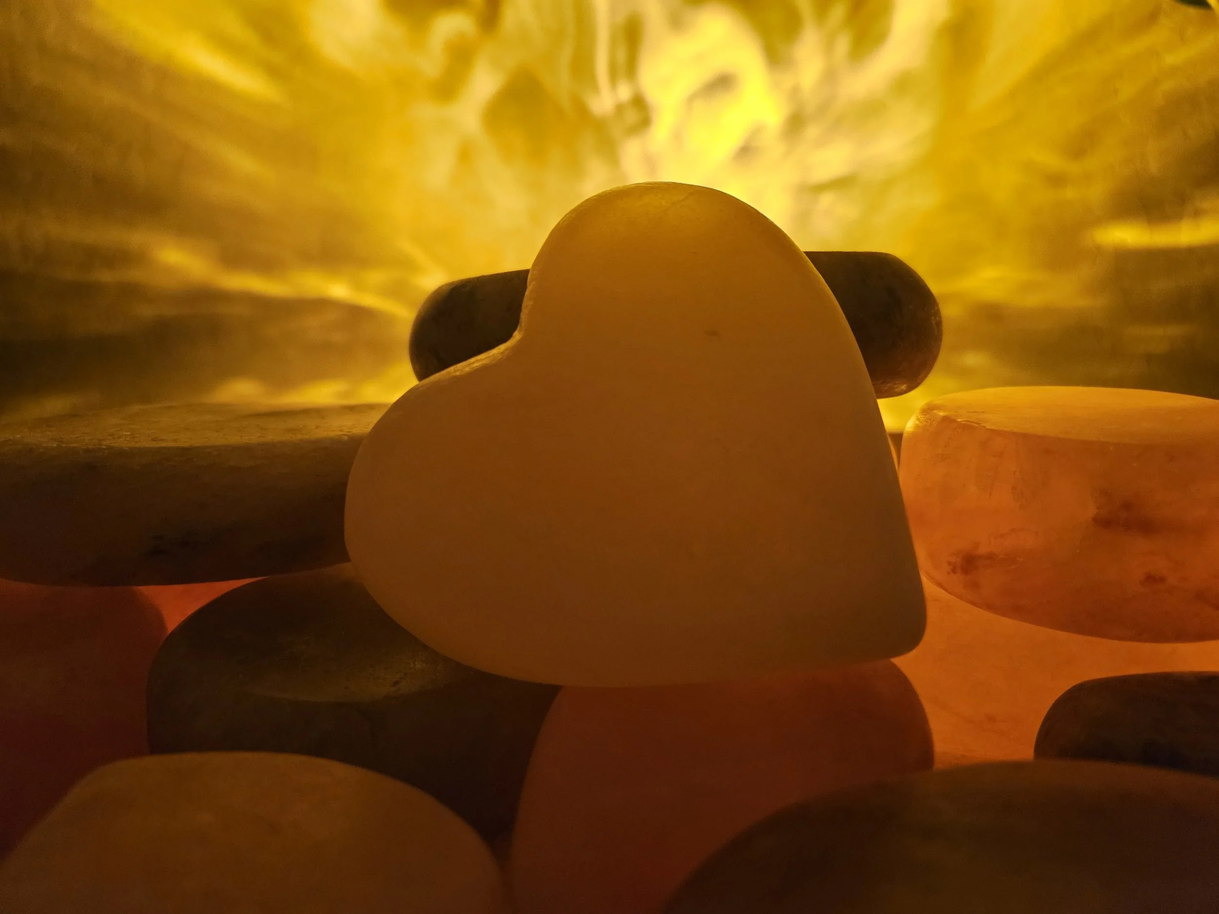 Close-up of heart-shaped stone with warm backlighting creating a glowing effect.